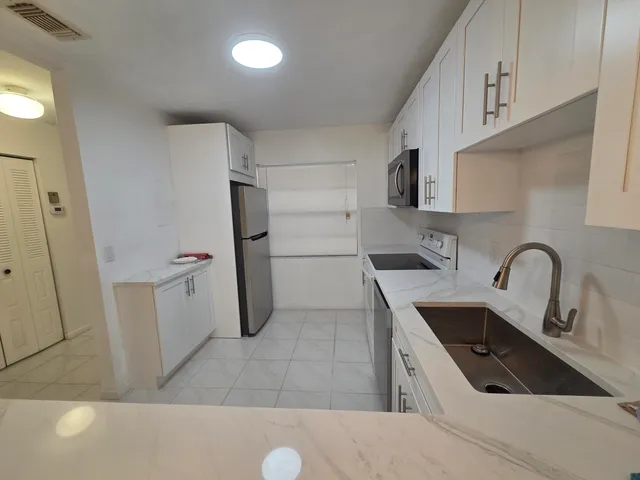 a kitchen with a sink a refrigerator and cabinets