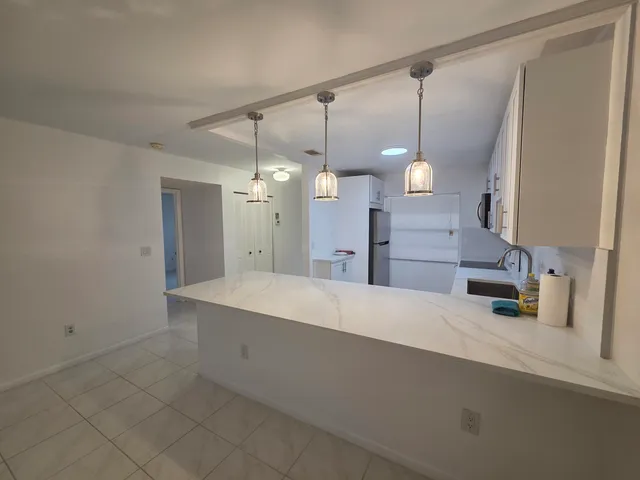 a large kitchen with a sink a counter and a refrigerator