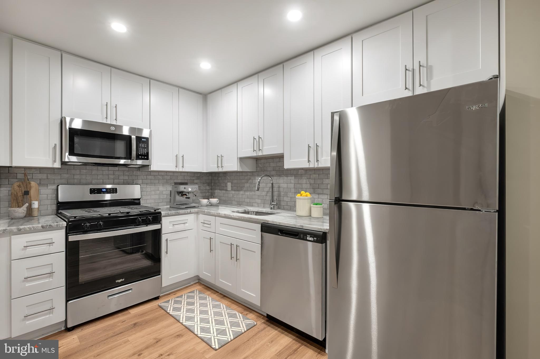 1218 Walnut Street, Unit 1204 Philadelphia, PA 19107 - Photo 2 of 11 a kitchen with stainless steel appliances granite countertop a refrigerator stove a sink and microwave