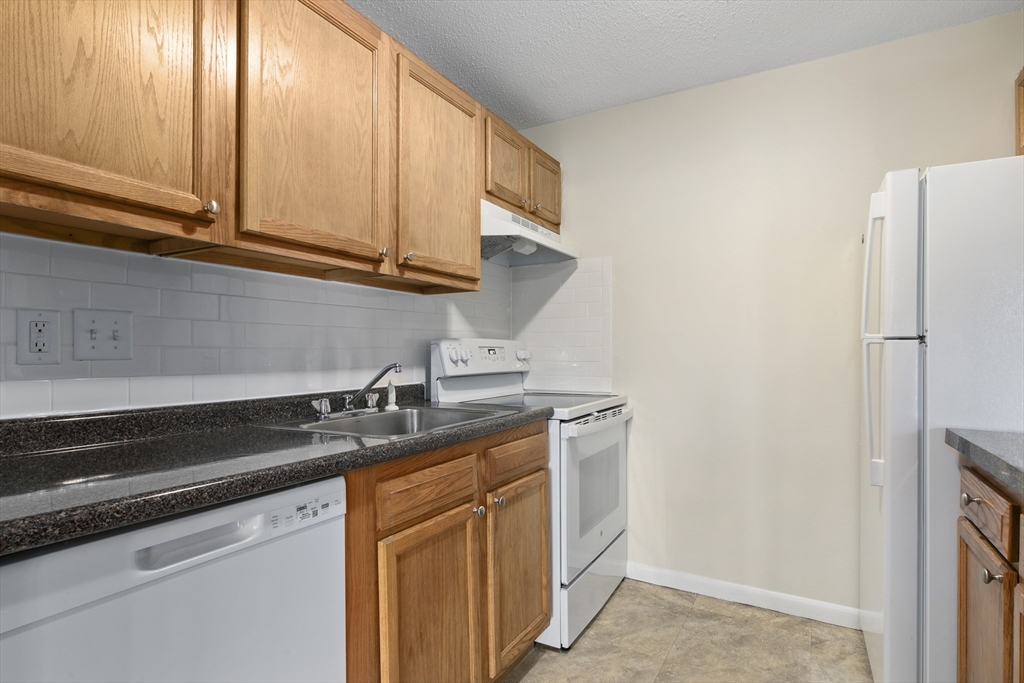 68 Main Street, Unit 17C Stoneham, MA 02180 - Photo 4 of 13 a kitchen with stainless steel appliances granite countertop white cabinets and a refrigerator