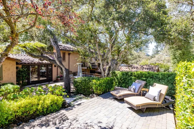 a view of a patio with couches and a table and chairs with wooden fence and plants