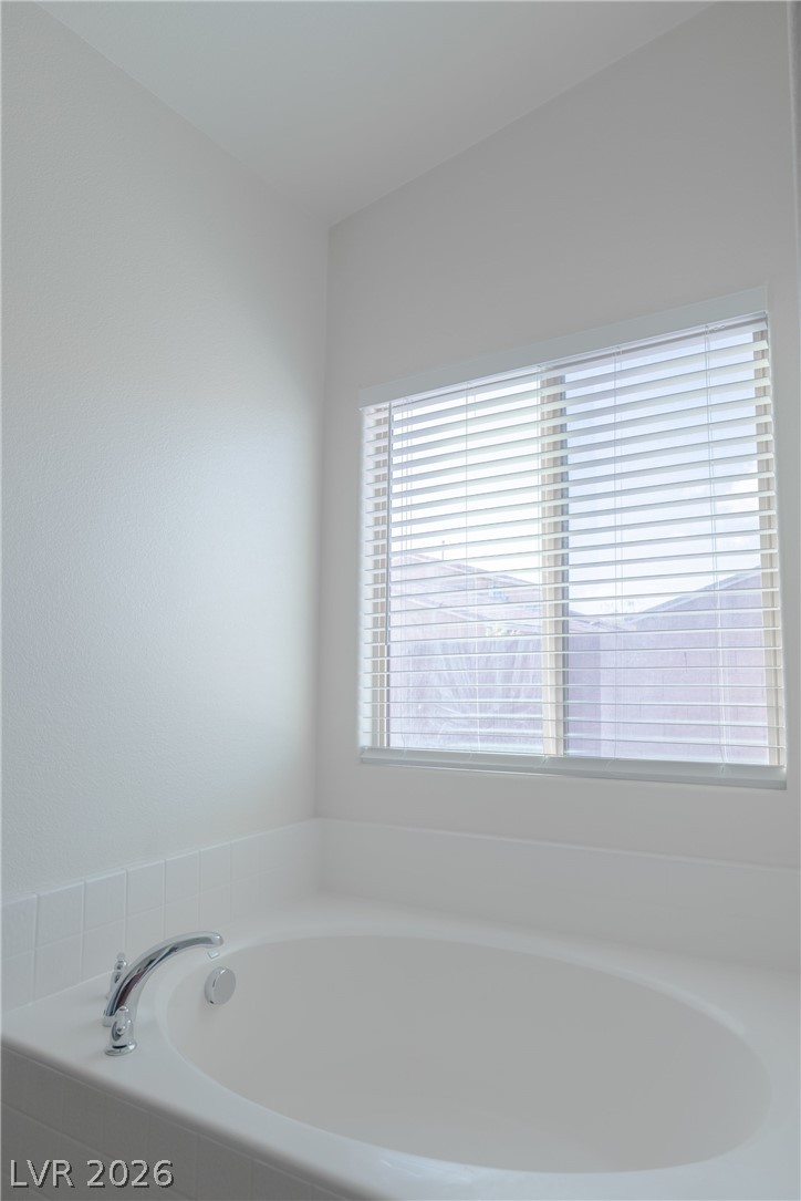 8079 Buffalo Ranch Avenue Las Vegas, NV 89147 - Photo 23 of 29 A deep soaking tub sits beneath a wide window with integrated blinds.