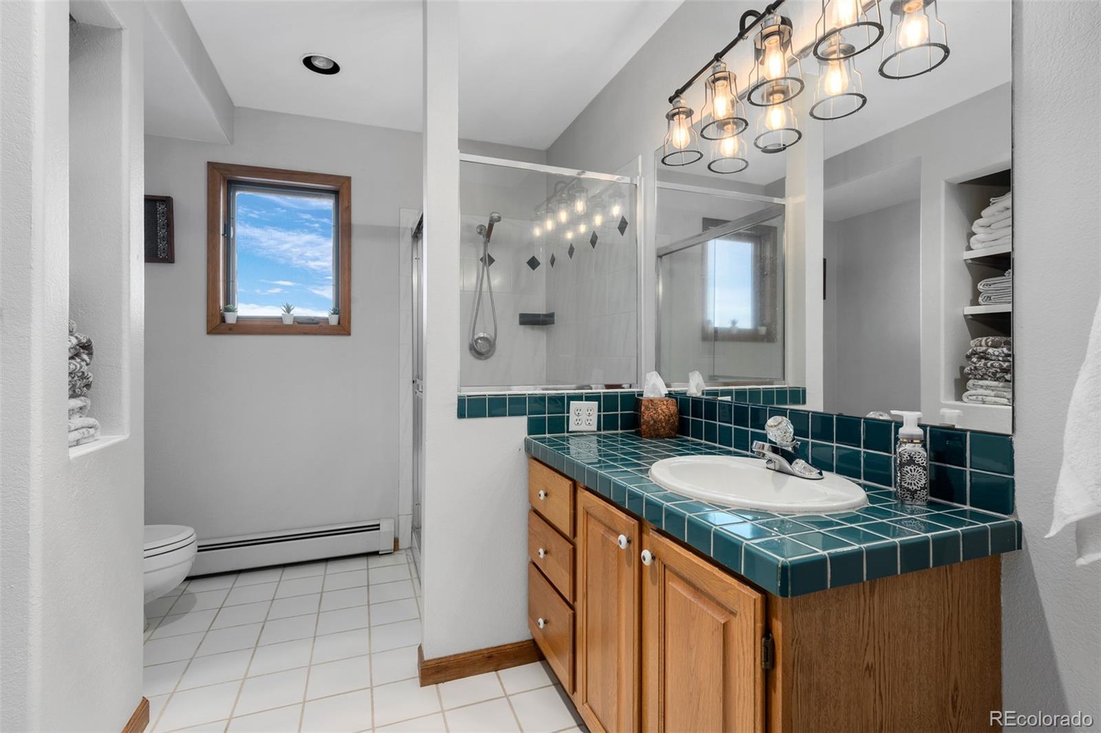 4205 West Parkridge Road Sedalia, CO 80135 - Photo 48 of 50 a bathroom with a granite countertop sink a large mirror and a shower