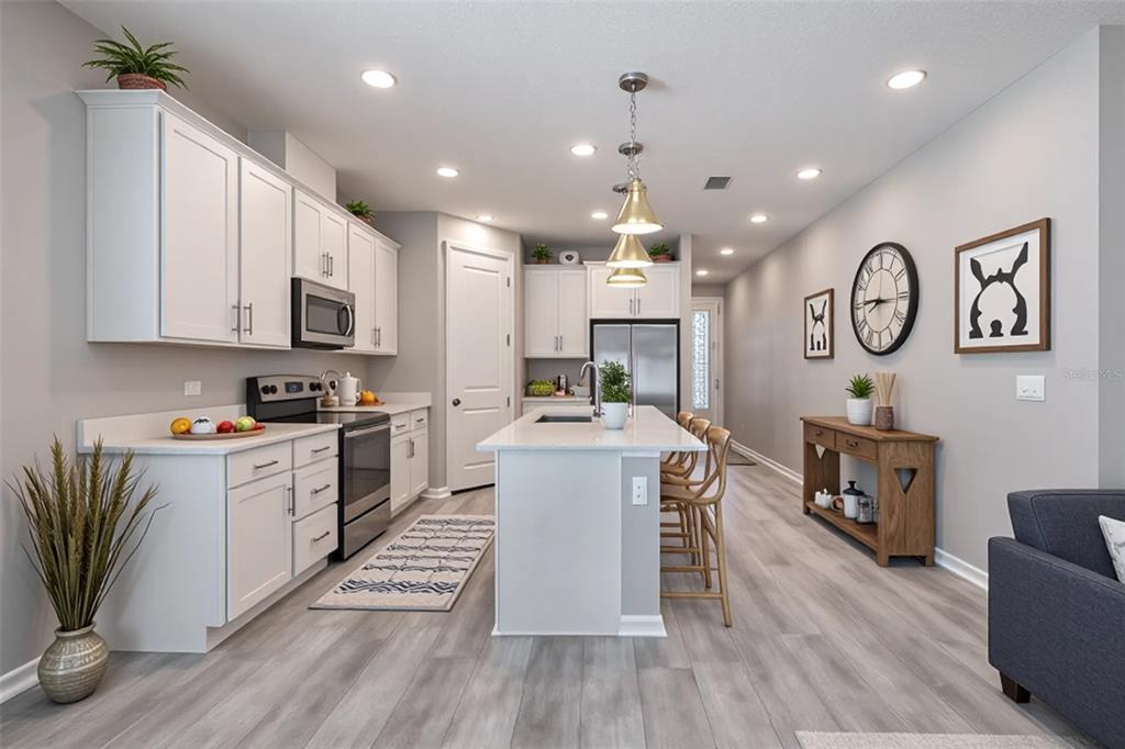 10361 Church Hammock Road Leesburg, FL 34788 - Photo 13 of 46 a large kitchen with stainless steel appliances kitchen island granite countertop a large stove a sink dishwasher and white cabinets with wooden floor