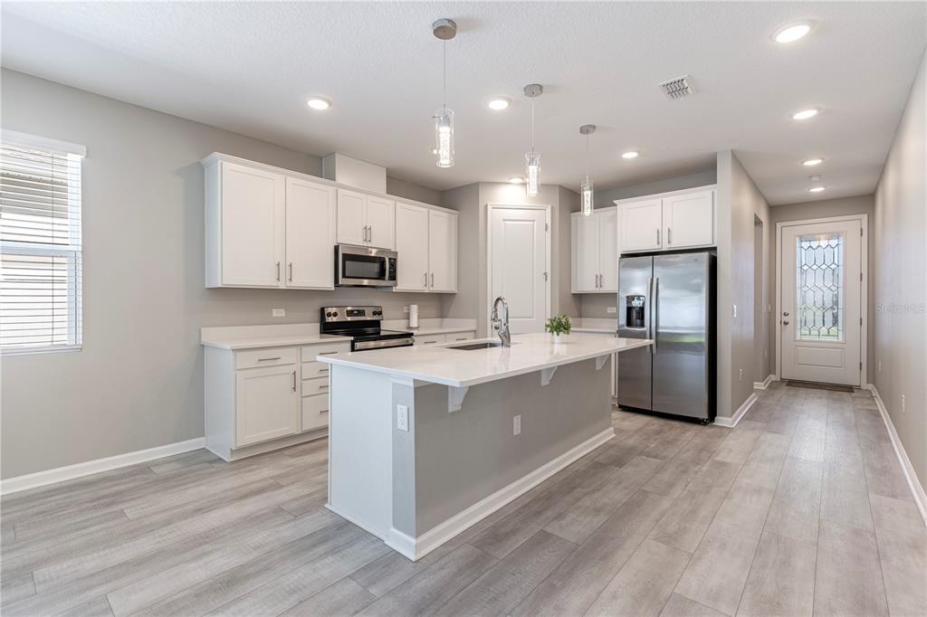 10361 Church Hammock Road Leesburg, FL 34788 - Photo 10 of 46 a kitchen with stainless steel appliances granite countertop a refrigerator sink and white cabinets