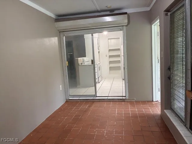 a view of an empty room with window and chandelier fan