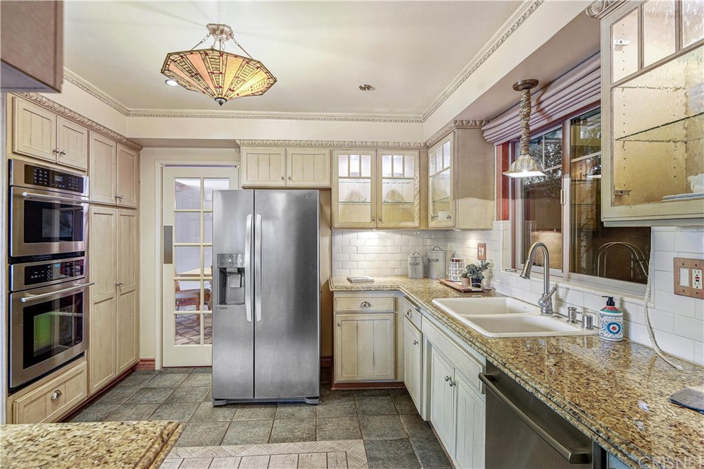 15098 Rayneta Drive Sherman Oaks, CA 91403 - Photo 16 of 43 a kitchen with stainless steel appliances granite countertop a sink refrigerator and cabinets