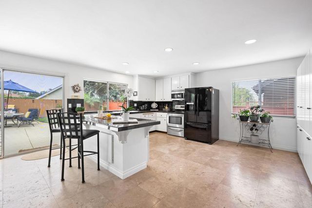 a kitchen with stainless steel appliances kitchen island granite countertop a refrigerator a stove a sink a dining table and chairs