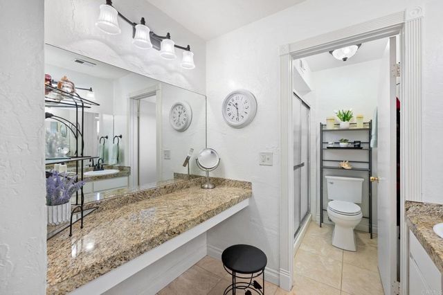 a bathroom with a granite countertop sink a toilet and a mirror