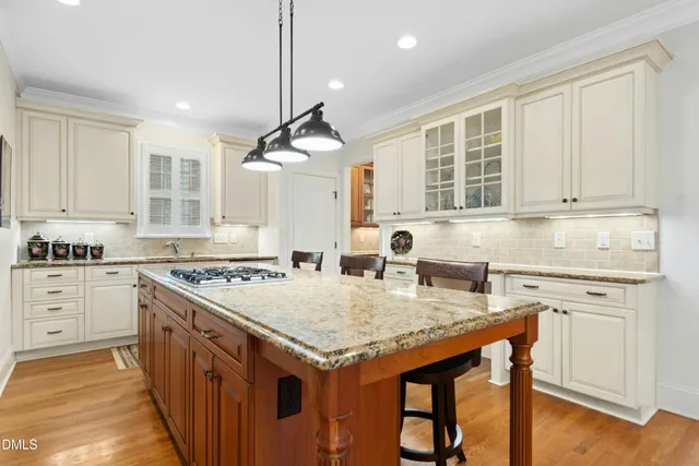 a kitchen with granite countertop a stove a sink dishwasher and white cabinets with wooden floor