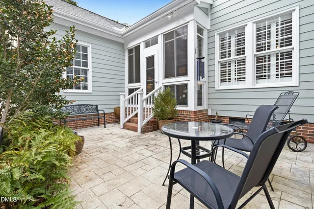 a balcony with table and chairs and potted plants