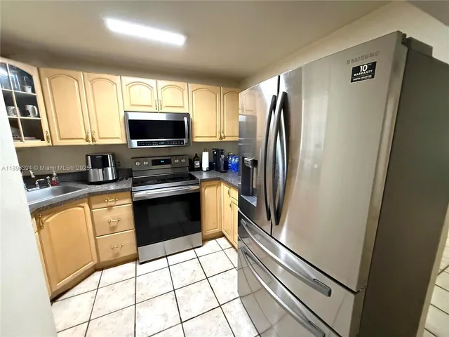 a kitchen with granite countertop a refrigerator a stove a microwave and a sink