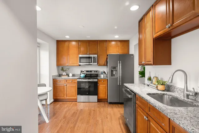 a kitchen with stainless steel appliances granite countertop a sink stove refrigerator and cabinets