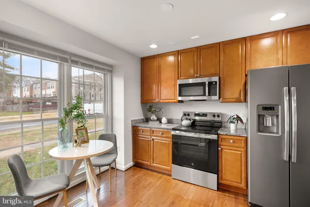 a kitchen with stainless steel appliances granite countertop a stove a refrigerator a microwave a dining table and chairs