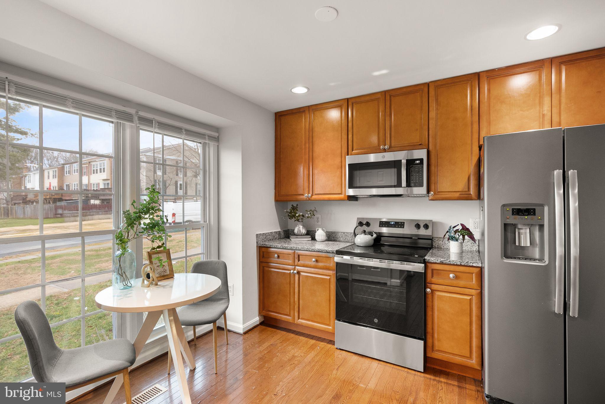 3203 Foothill Street Woodbridge, VA 22192 - Photo 7 of 57 a kitchen with stainless steel appliances granite countertop a stove a refrigerator a microwave a dining table and chairs