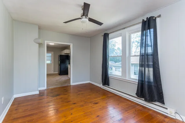 a view of empty room with wooden floor and fan