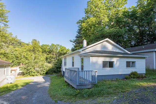 a view of a house with a yard plants and large tree