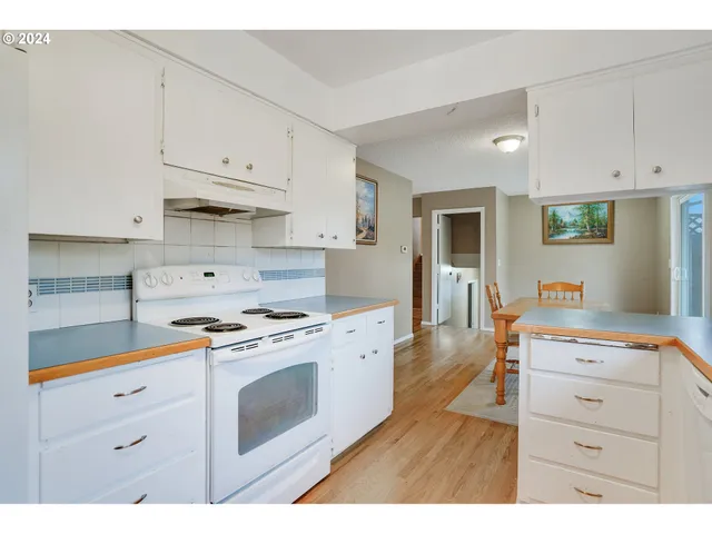 a kitchen with stainless steel appliances a stove a sink and white cabinets