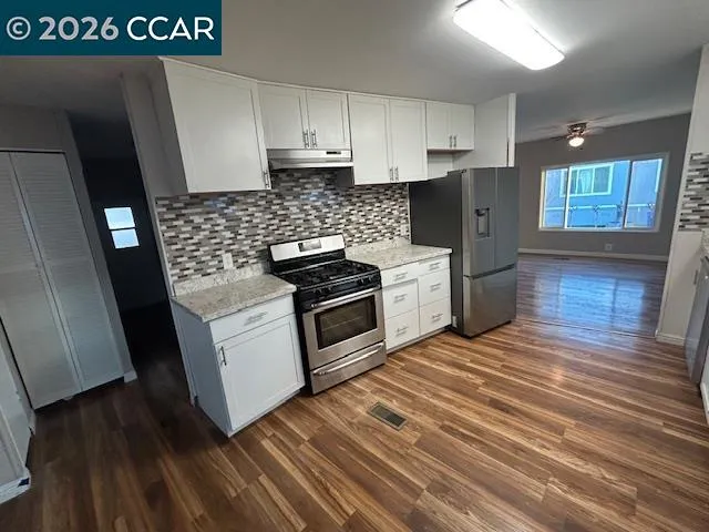 a kitchen with granite countertop a sink a stove and refrigerator