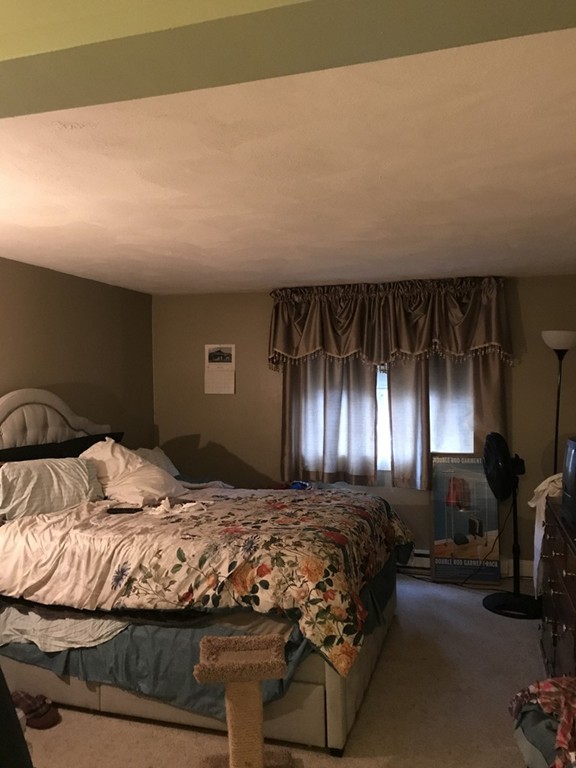 90-92 Sandwich Road, Unit 5 Bourne, MA 02532 - Photo 8 of 12 a bedroom with a large bed and a chandelier