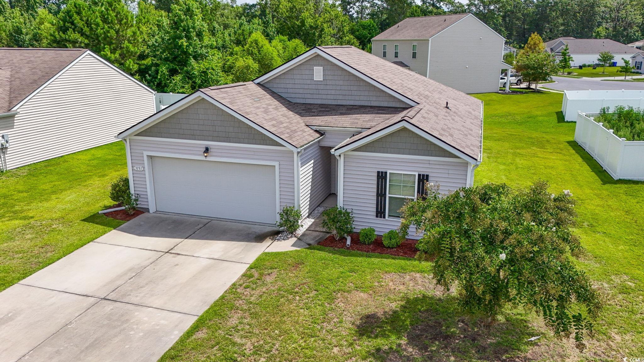 View of front of home with an attached garage, driveway, a front yard, and a shingled roof
