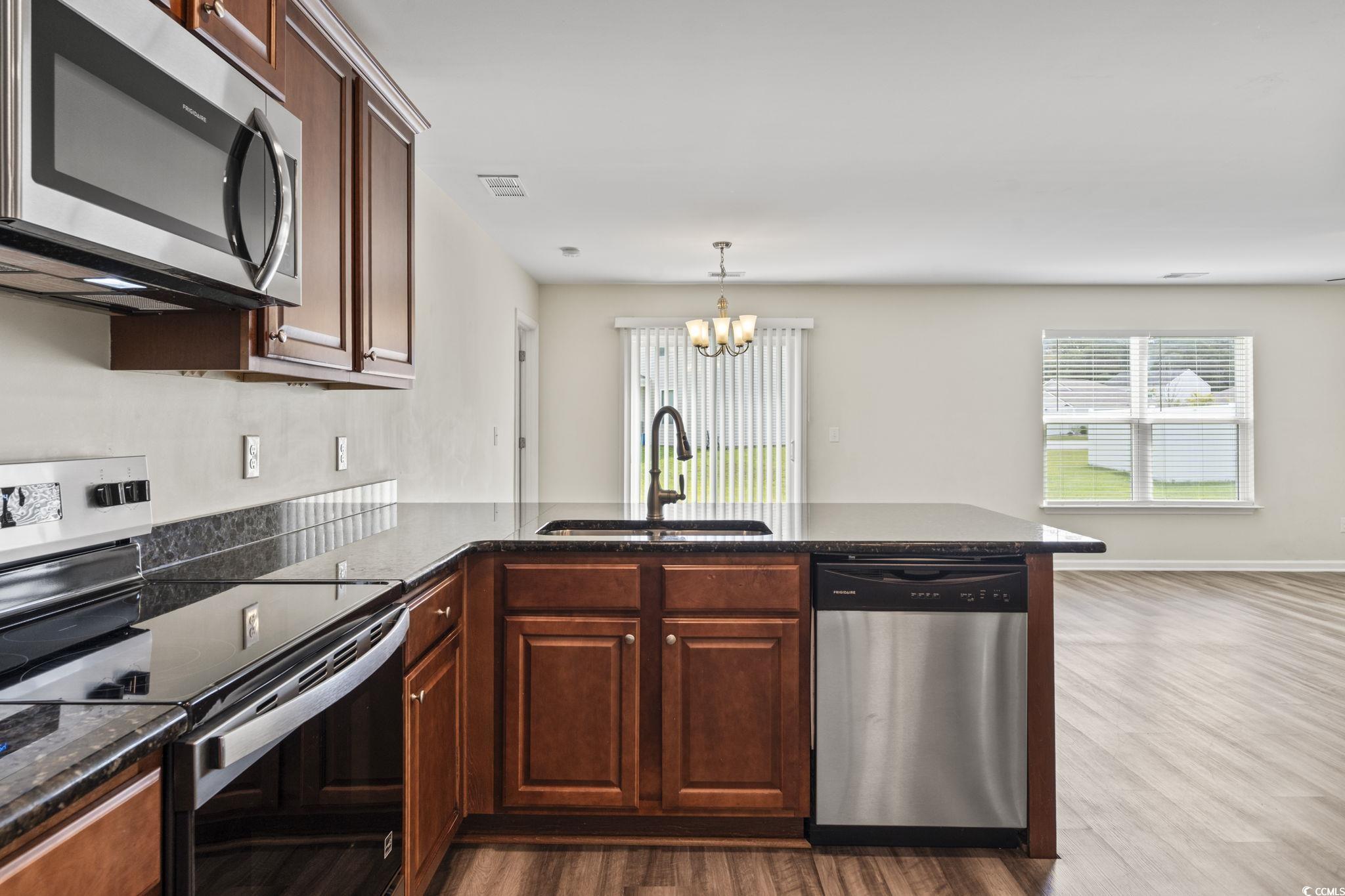 3151 Holly Loop Conway, SC 29527 - Photo 13 of 31 Kitchen with stainless steel appliances, a peninsula, a chandelier, dark wood-style floors, and dark stone counters