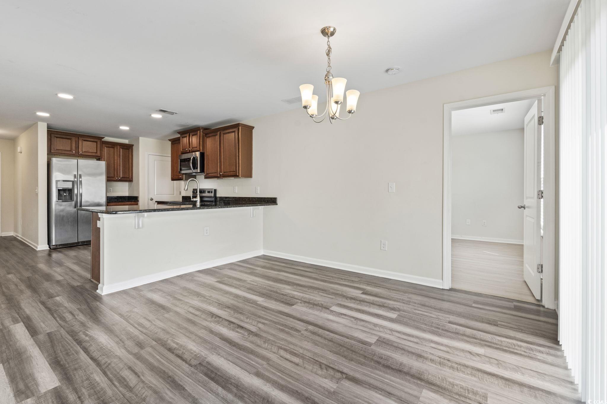 3151 Holly Loop Conway, SC 29527 - Photo 15 of 31 Kitchen with dark countertops, appliances with stainless steel finishes, a peninsula, a chandelier, and wood finished floors