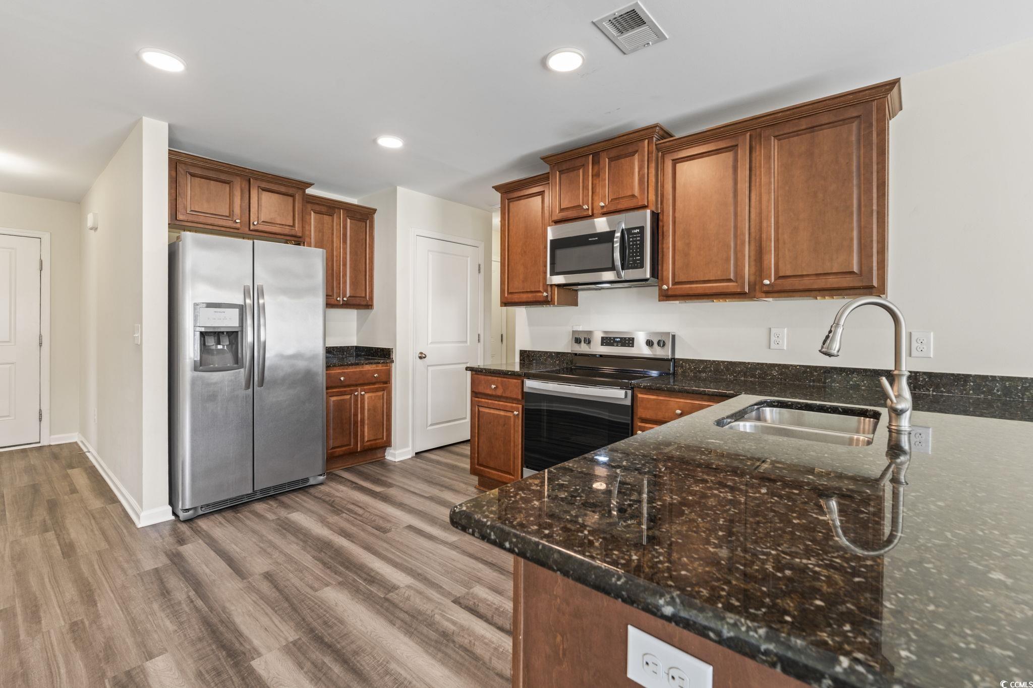 3151 Holly Loop Conway, SC 29527 - Photo 2 of 31 Kitchen featuring appliances with stainless steel finishes, recessed lighting, light wood finished floors, dark stone counters, and brown cabinetry