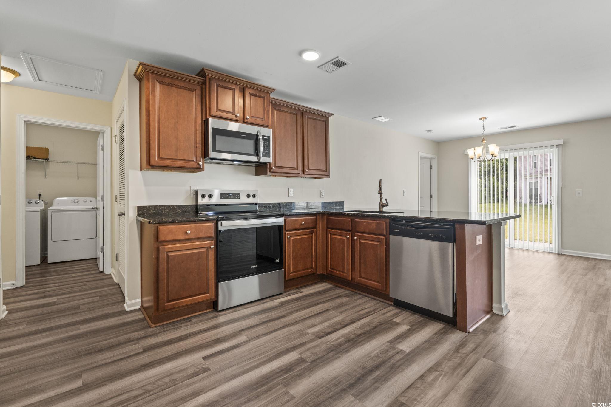 3151 Holly Loop Conway, SC 29527 - Photo 8 of 31 Kitchen featuring washer and clothes dryer, stainless steel appliances, a peninsula, and brown cabinets