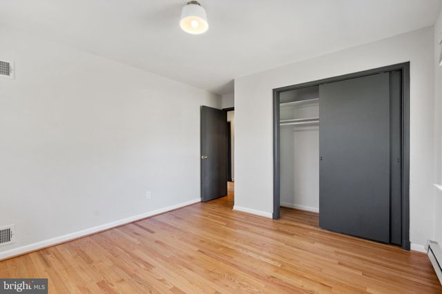 a view of an empty room with wooden floor and closet