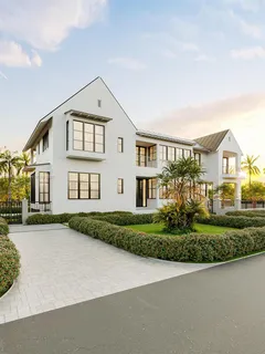 a view of a white house next to a yard with big trees
