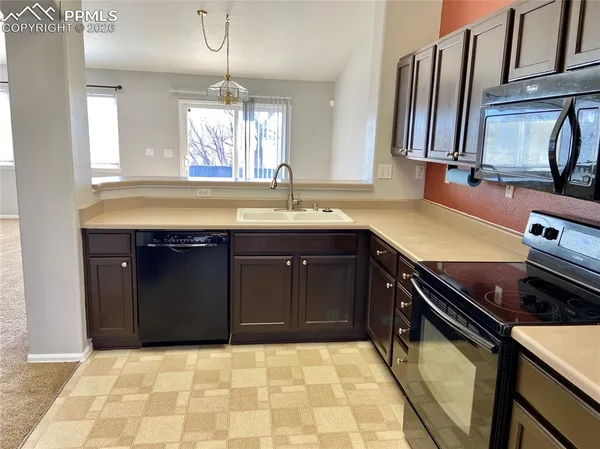a kitchen with a sink a stove cabinets and a window