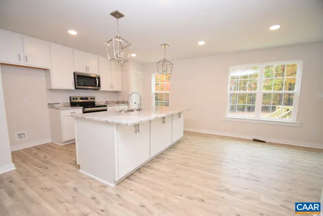 a kitchen with kitchen island granite countertop a stove top oven a sink a counter top space and cabinets