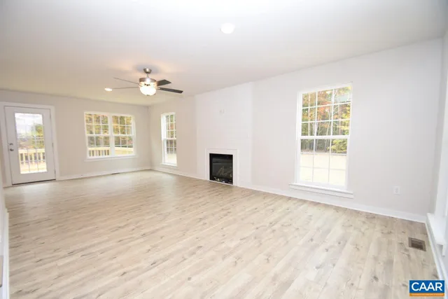 a view of an empty room with a window and a kitchen