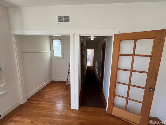 an empty room with wooden floor and entrance