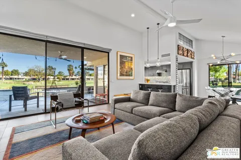 a living room with furniture kitchen view and a large window