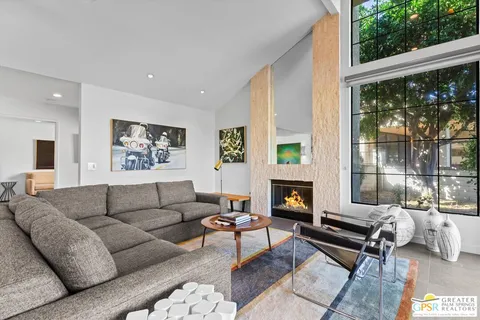 a living room with furniture a fireplace and a floor to ceiling window