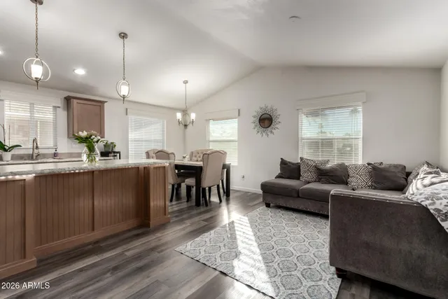 a living room with furniture kitchen area and a wooden floor