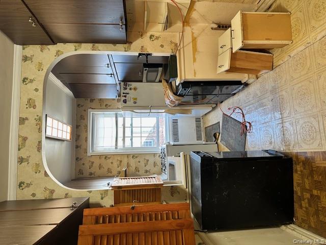 15 Gaynor Avenue, Unit 2H Manhasset, NY 11030 - Photo 5 of 7 Kitchen with wallpapered walls, radiator heating unit, arched walkways, ornamental molding, and refrigerator