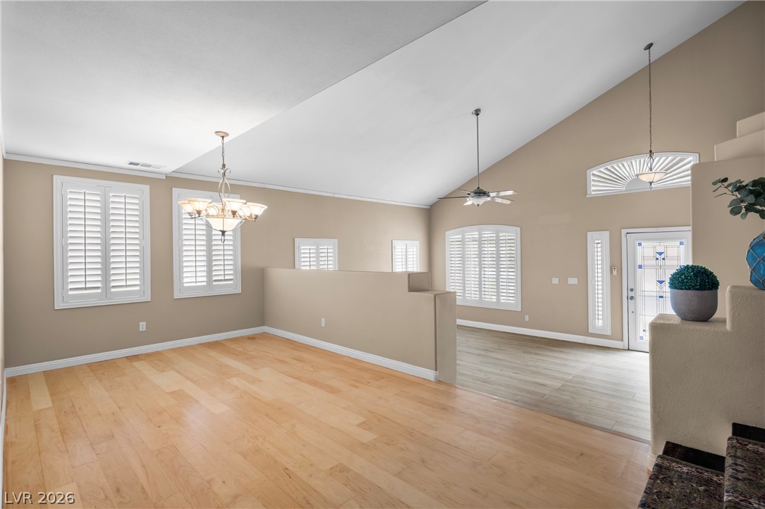 708 Vortex Avenue Henderson, NV 89002 - Photo 10 of 71 Natural light illuminates this spacious living area, featuring high vaulted ceilings and polished hardwood flooring.