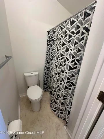 a bathroom with a toilet and a shower curtain