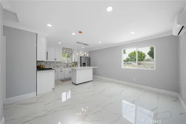 a kitchen with stainless steel appliances kitchen island granite countertop a refrigerator a sink a stove a dining table and chairs