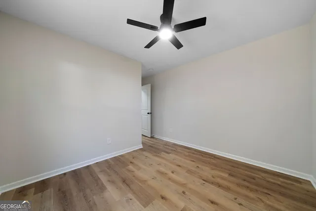 an empty room with wooden floor and ceiling fan