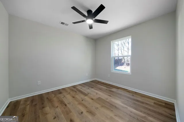 an empty room with windows and fan