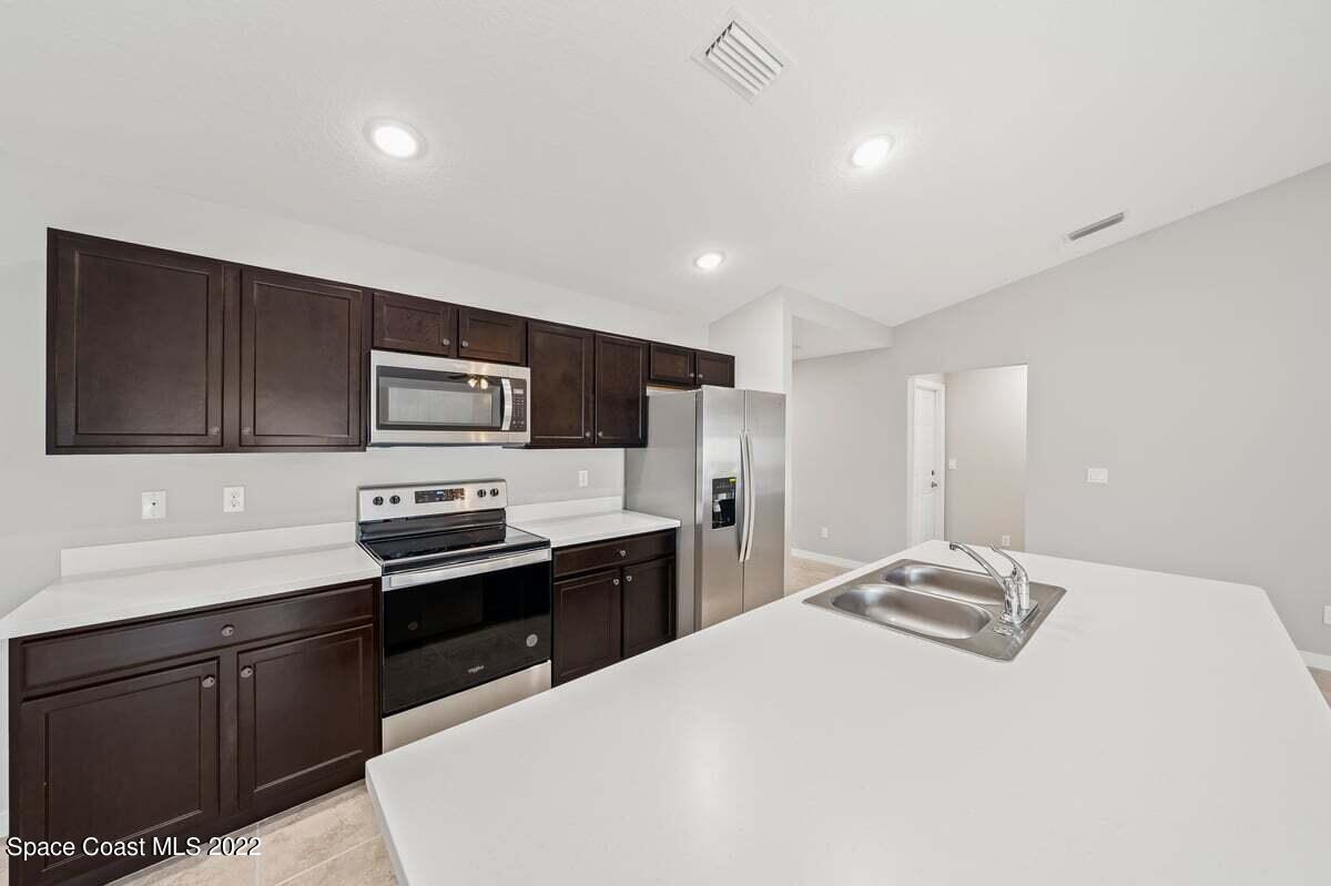 1111 Ver Circle Northeast Palm Bay, FL 32905 - Photo 11 of 30 a kitchen with stainless steel appliances a sink stove refrigerator and cabinets