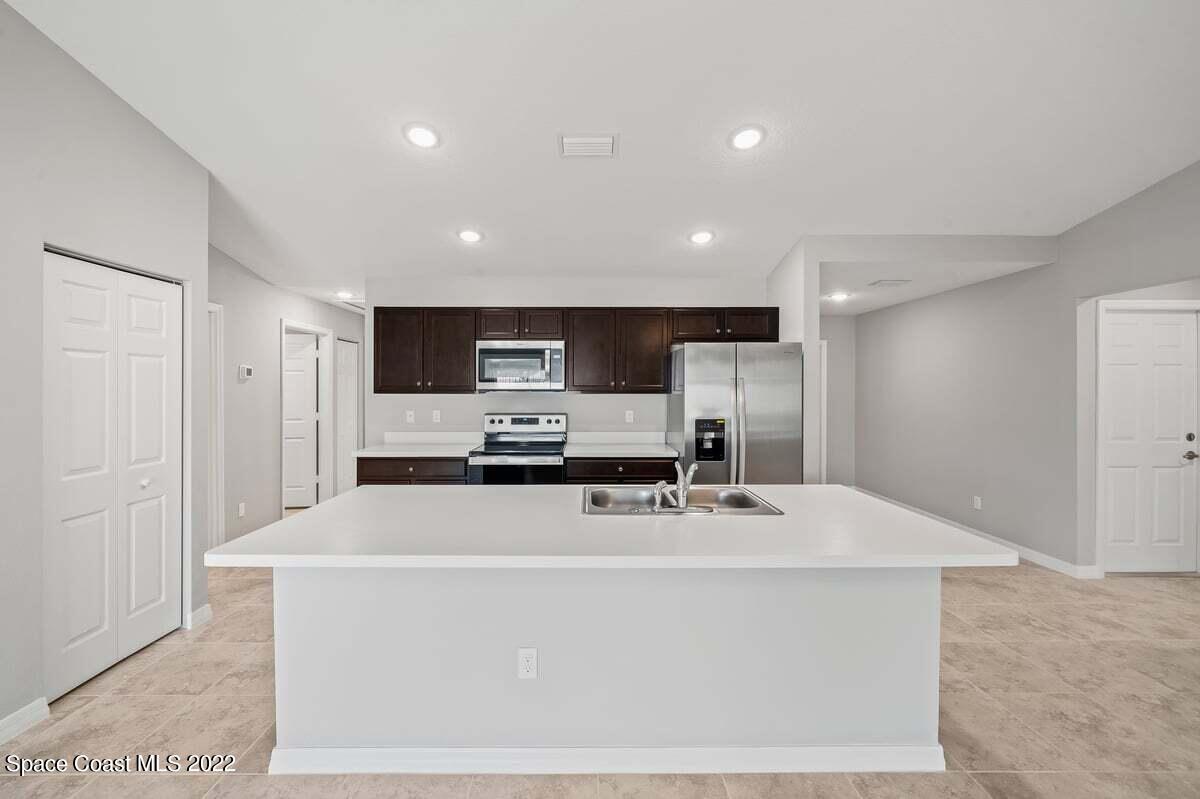 1111 Ver Circle Northeast Palm Bay, FL 32905 - Photo 9 of 30 a room with stainless steel appliances a refrigerator a sink dishwasher with granite countertops and cabinets