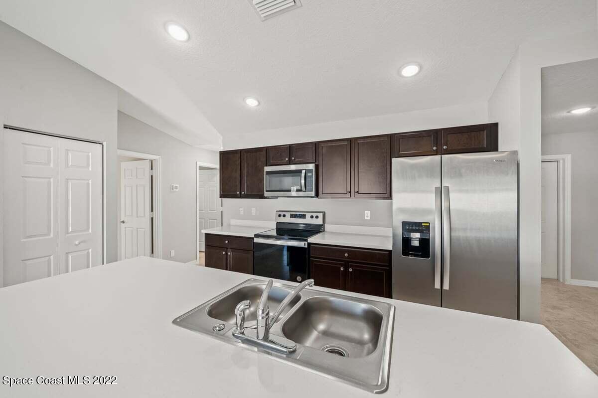 1111 Ver Circle Northeast Palm Bay, FL 32905 - Photo 10 of 30 a kitchen with stainless steel appliances granite countertop a refrigerator a stove and a sink