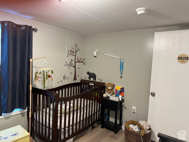 1375 West 500th North, Unit 95 Provo, UT 84601 - Photo 12 of 19 Bedroom with a textured ceiling, light wood-style floors, and a crib