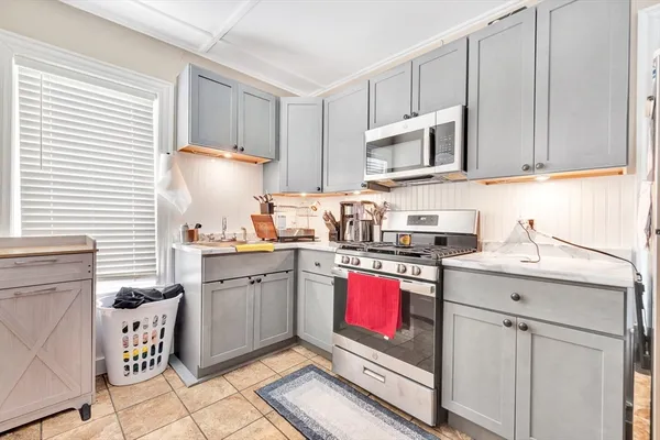 a kitchen with stainless steel appliances granite countertop a stove top oven a sink a dining table and chairs with wooden floor