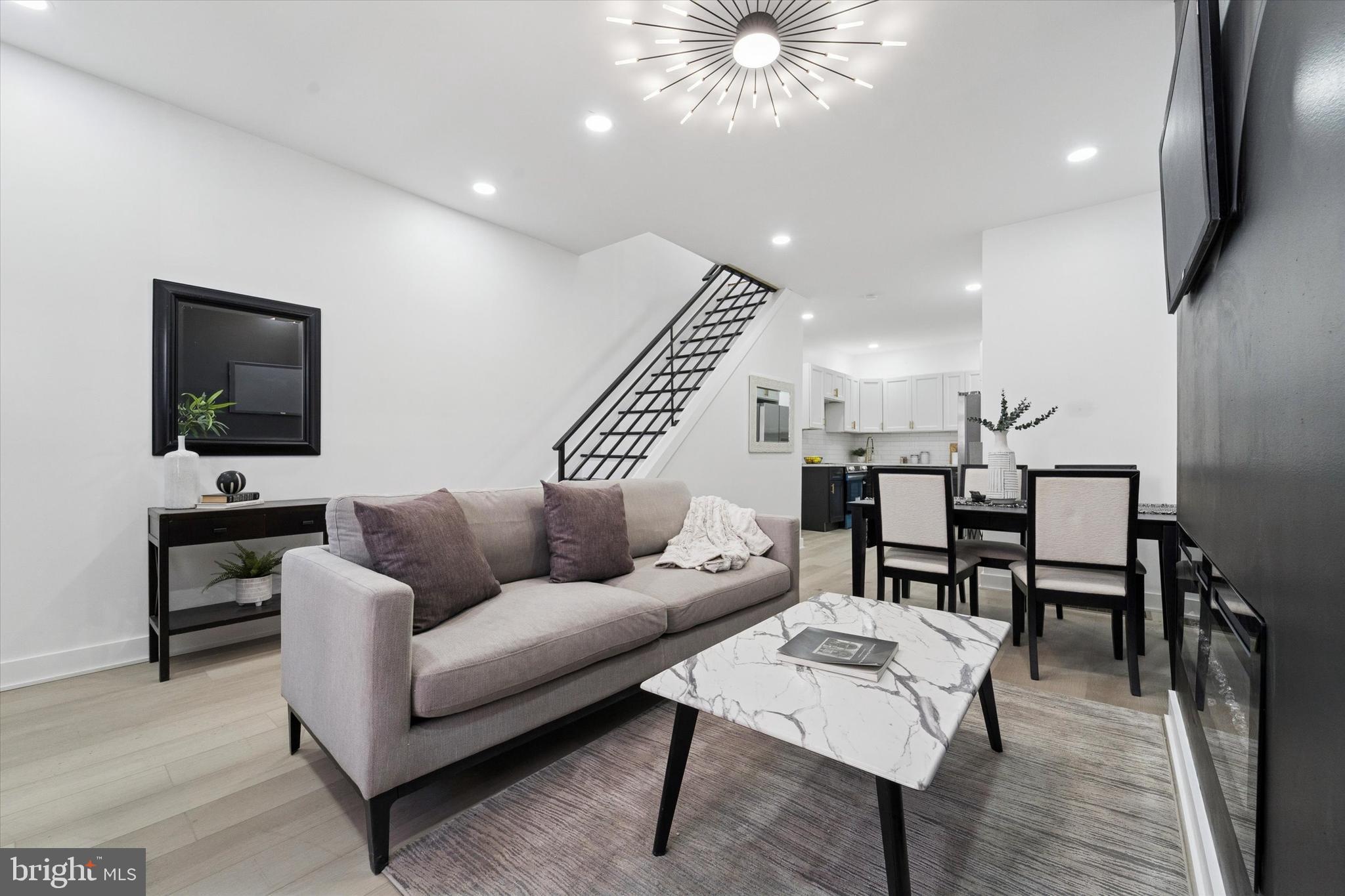 a living room with furniture a flat screen tv and kitchen view
